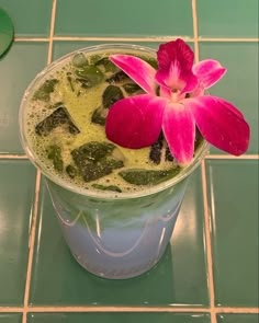 a pink flower sitting on top of a cup filled with liquid