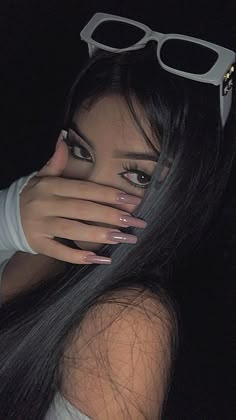 a woman with long black hair and glasses covering her face in front of the camera