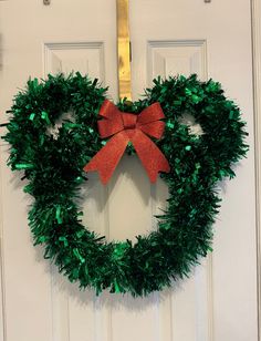 a green wreath with a red bow hanging on a door