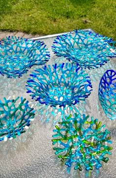 four blue and green vases sitting on top of a glass tablecloth covered surface