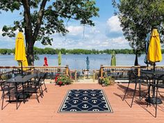 an outdoor patio with tables, chairs and umbrellas on the deck next to water