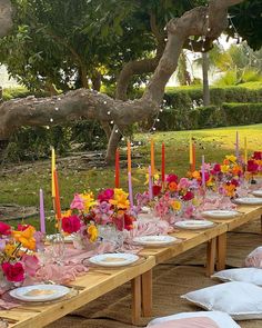 a long table set up with candles, plates and napkins for an outdoor dinner