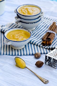 two bowls filled with soup next to some cinnamons and anise on a table