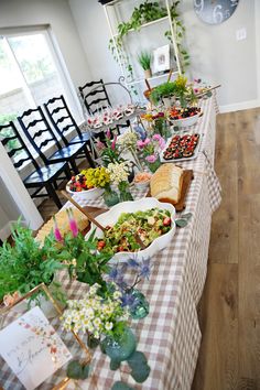 a long table covered with lots of food and flowers on top of wooden floors next to a clock