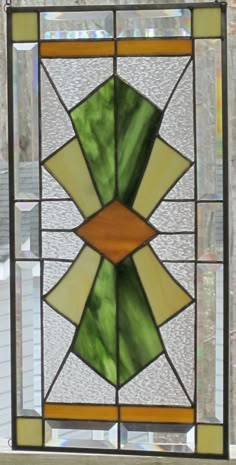 a stained glass window with green and yellow designs on the bottom half, in front of a house