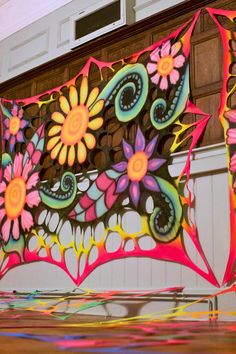 a colorful kite is flying in the air with flowers painted on it's side