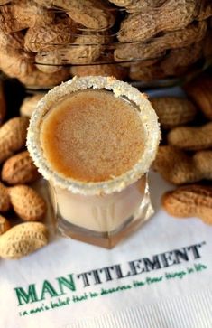 peanut butter in a small glass cup next to peanuts on a napkin that says man - tittlement