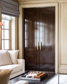 a living room with a couch, coffee table and large wooden door in the corner