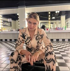 a woman sitting on top of a suitcase in a room with black and white tiles