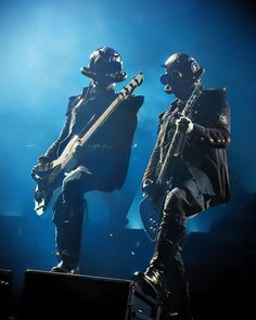 two metal musicians are performing on stage