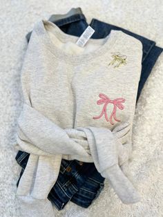 Our sweet little ribbon bow sweatshirt is not only on trend this season but completely adorable!   Cute and cozy for any girly girl you know or for yourself!  So go ahead, throw a ribbon around your ponytail and pair this cutie with your favorite jeans or leggings! Shown here in oatmeal with rose thread! Features: 8 oz., 50% USA cotton, 50% polyester Pill-resistant air jet yarn Made with 50% sustainably and fairly grown USA cotton Feature: Pill-resistant air jet yarn These are unisex sizing, fit Cute Embroidered Sweatshirt Gift, Cute Custom Embroidery Sweatshirt For Winter, Cute Winter Sweatshirt With Custom Embroidery, Cute Letter Embroidery Sweatshirt For Winter, Clothes With Bows, Bow Clothing, Bow Clothes, Bow Sweatshirt, Monogram Bow