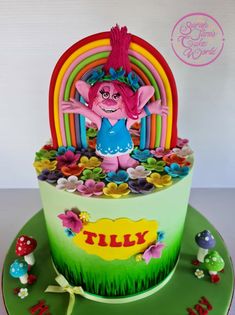 a birthday cake decorated with an image of a troll in the grass and rainbows