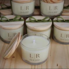 several candles sitting on top of a wooden table next to some containers with lids and bows