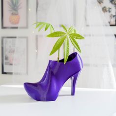 a purple shoe with a plant in it sitting on a white table next to pictures