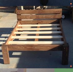 a wooden bed frame sitting on top of a sidewalk