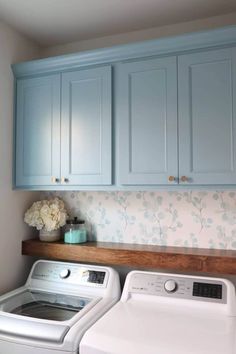 a washer and dryer in a small laundry room with blue cabinetry on the wall