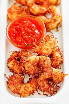 fried shrimp with ketchup and sauce on a white platter, ready to be eaten