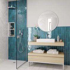 a bathroom with blue tiles and white fixtures, including a shower head mounted on the wall