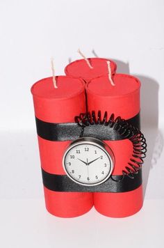 four red candles with black stripes and a clock on the top one is wrapped in twine