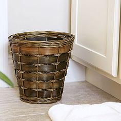 a brown basket sitting on the floor next to a white towel