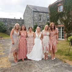 a group of women standing next to each other in front of a stone building with ivy covered walls