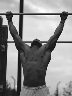 a shirtless man is doing pull ups on a bar