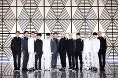 a group of men standing next to each other in front of a wall with geometric designs