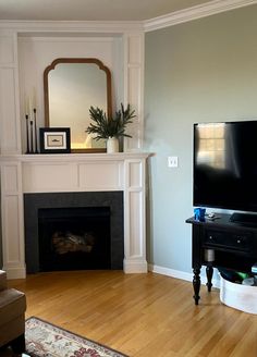 a living room with a fireplace, mirror and television on the mantel above it