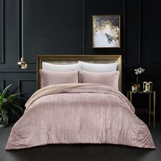 a bed with a pink comforter and two pillows on it in a dark room