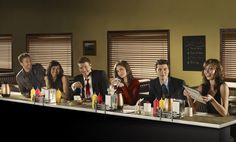 a group of people sitting at a table in front of blinds with the words bones on it