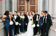 a bride and groom with their bridal party in front of the doors of an old building