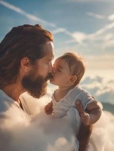 a man with long hair holding a baby in his lap and kissing him on the cheek