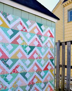 a colorful quilt sitting on top of a wooden fence