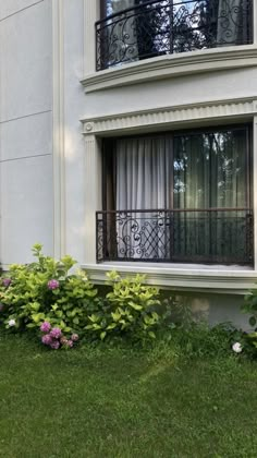 a window with curtains and flowers in front of it on the side of a building