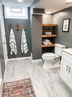 a bathroom with two towels hanging on the wall and a rug in front of it