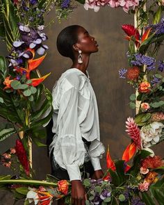 a woman standing in front of flowers and greenery