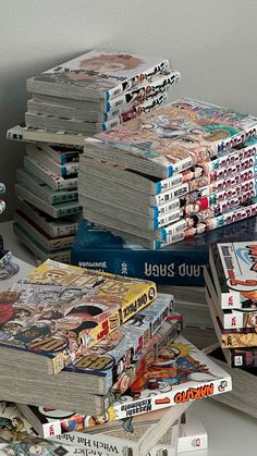 a stack of books sitting on top of a white table next to a remote control