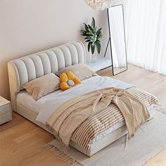 a bedroom with a bed, mirror and plant in the corner on the floor next to it