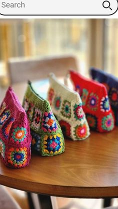 colorful crocheted purses sitting on top of a wooden table