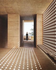 a person standing in an open area with a bench and wall made out of squares