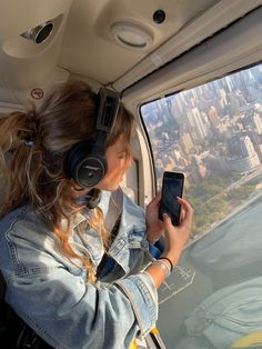 a woman is looking at her cell phone while flying in an airplane over the city