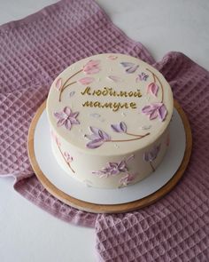 a decorated cake sitting on top of a white plate next to a pink napkin and purple cloth