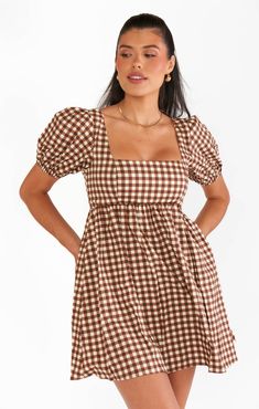 a woman in a brown and white checkered dress with her hands on her hips