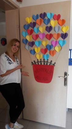 a woman standing in front of a door decorated with paper hearts and an air balloon