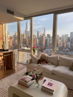 a living room filled with furniture next to large windows and a view of the city