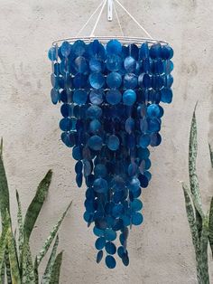 a chandelier made out of blue glass beads hangs from a metal rod next to cacti