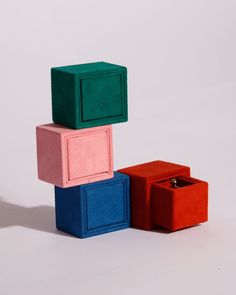 three different colored boxes sitting next to each other on top of a white surface,