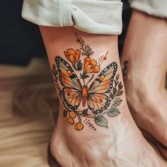 a woman's foot with an orange butterfly tattoo on her left ankle and flowers in the middle