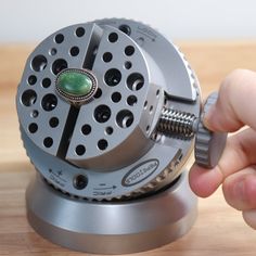 a person is opening the top of a metal device on a wooden surface with their fingers