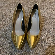 a pair of gold shoes sitting on top of a carpet